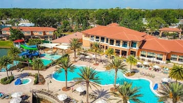 A resort with multiple swimming pools, palm trees, and a large building with a red roof.