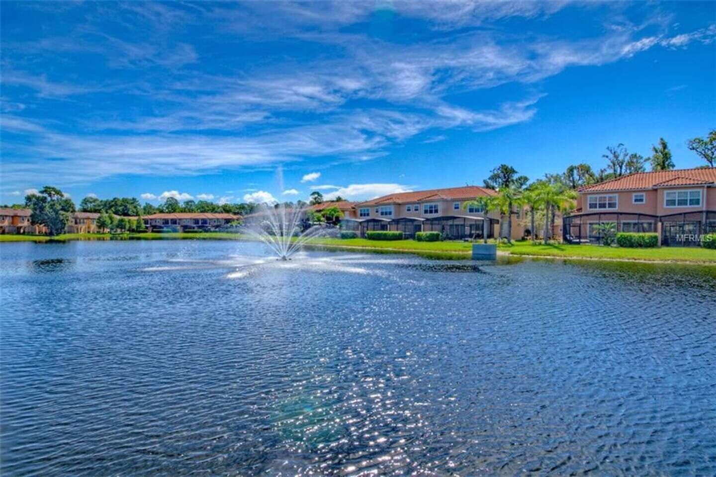 A lake with a fountain, surrounded by residential buildings with a red roof.