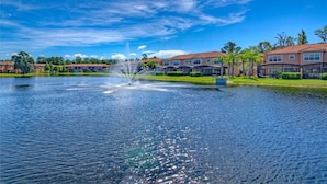 A lake with a fountain, surrounded by residential buildings with a red roof.