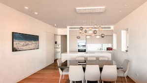 Une cuisine moderne avec des meubles blancs, un îlot central et des luminaires suspendus.