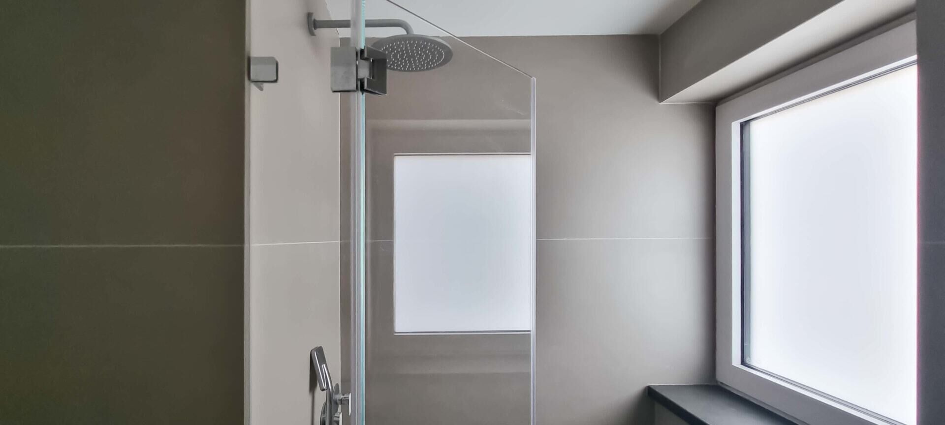 A modern bathroom with a shower, a toilet, and a window.