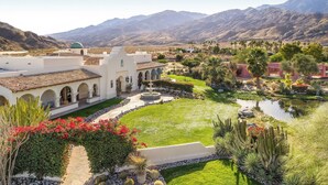 A courtyard with a fountain, cactus plants, and a pool. - The Pond Estate by Avantstay Maximalist Designer Compound w/ 2 Casitas, Indoor + Outdoor Pools, Tennis Court, & Gorgeous Mountain Views 12k Sqft (Palm Springs)