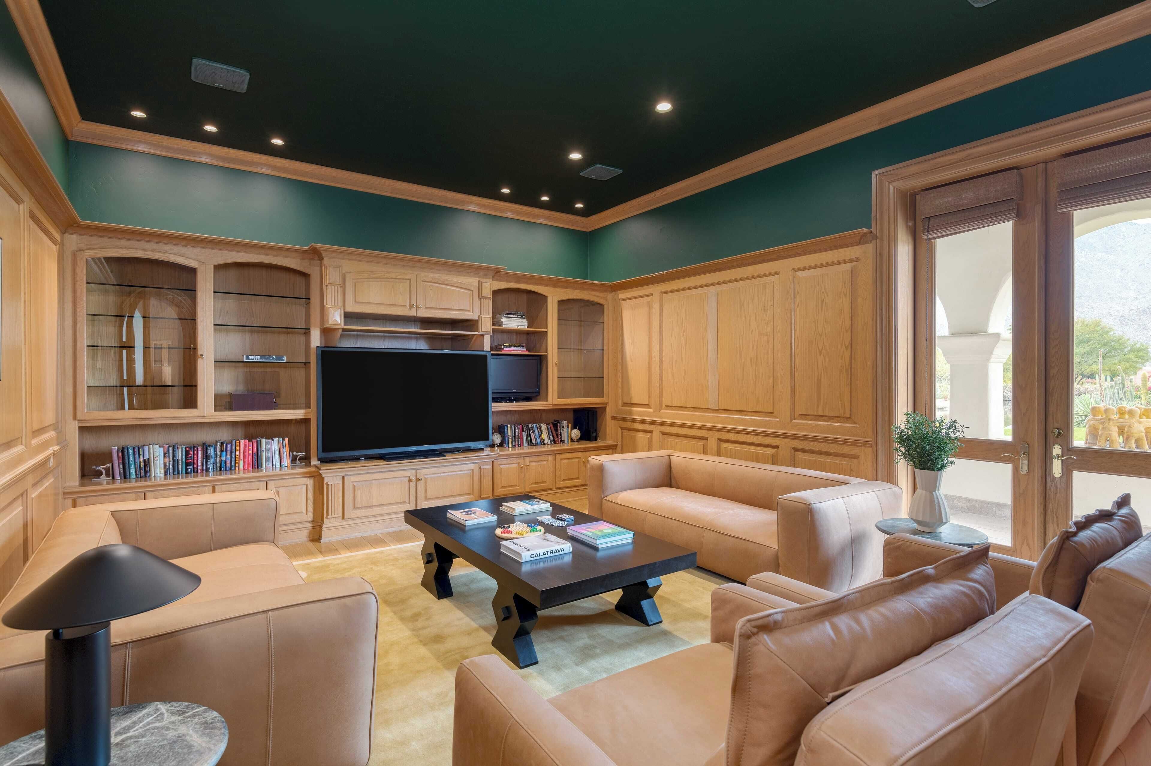 Un salón espacioso con una televisión de pantalla plana grande, sofás de cuero, una mesa de centro y muebles de madera.