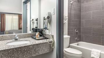Ein modernes Badezimmer mit einem Waschbecken aus Granit, einem Fön und einer Badewanne.