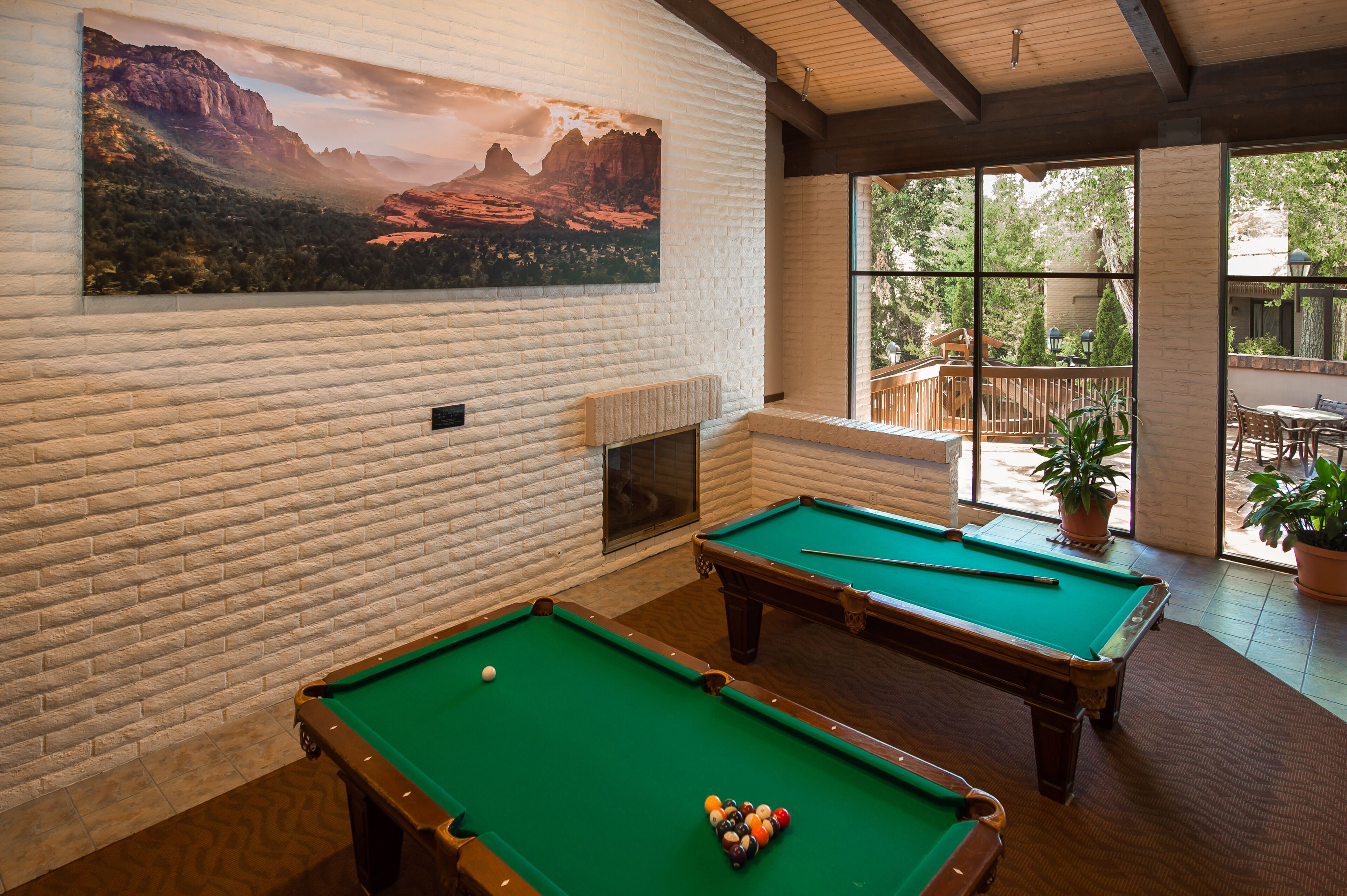 Une table de billard avec des billes, une cheminée et un tableau représentant un paysage accroché au mur.