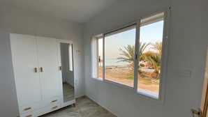 A room with a large window, a wardrobe, and a tiled floor.