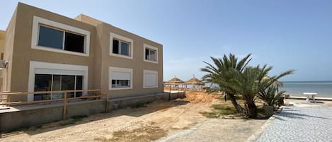 A modern building with large windows and a beach view.