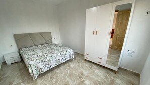 A bedroom with a bed, a wardrobe, and a nightstand.