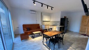 A compact living space with a dining area, kitchenette, and a sofa.