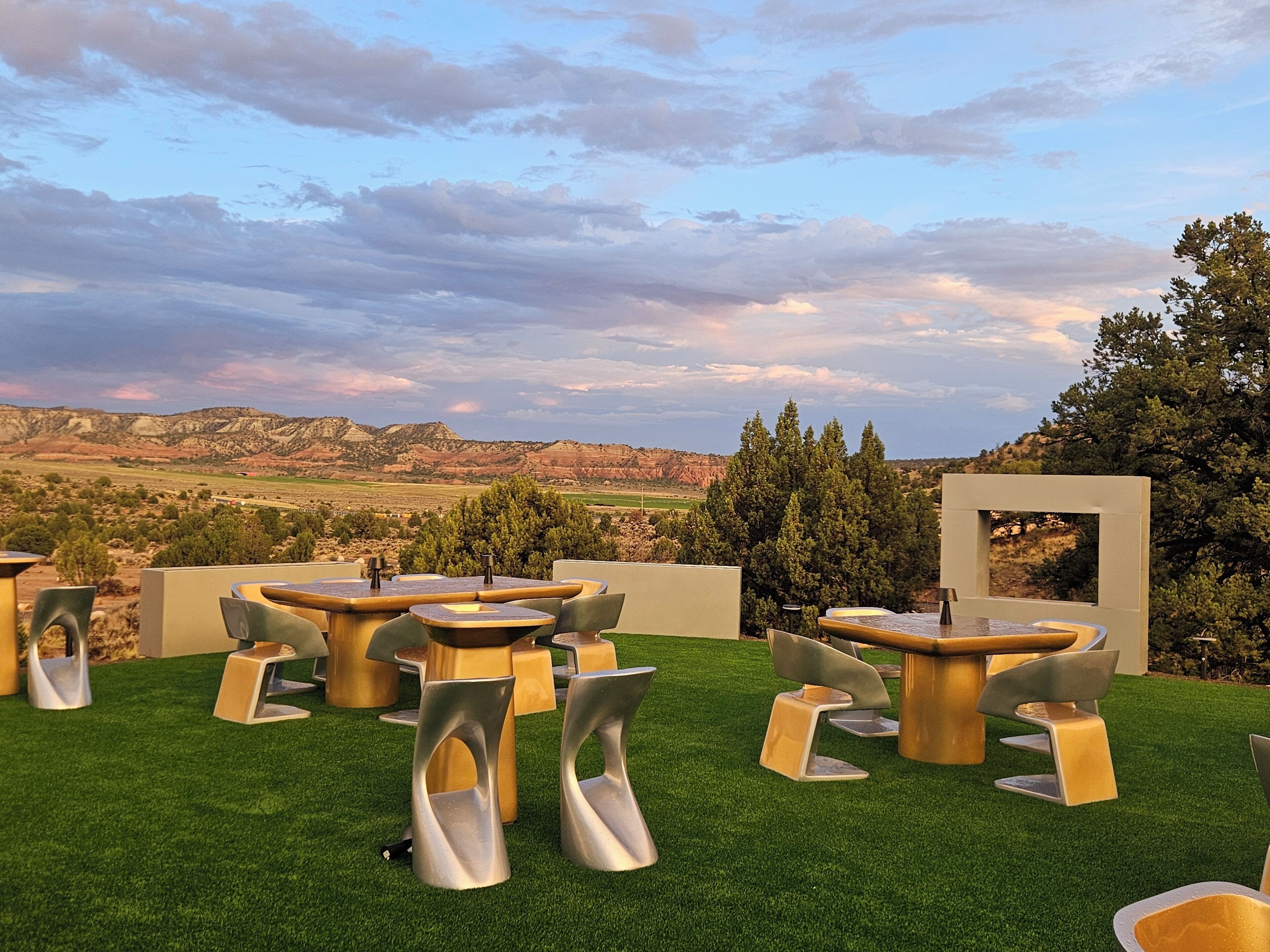 Un espace extérieur aménagé avec des tables et des chaises, offrant une vue sur le paysage environnant et un ciel dégagé.