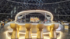 A modern interior with a central bar area featuring a unique, curved design and a geometric ceiling structure. - Clear Sky Resorts- Bryce Canyon Unique Stargazing Domes (Cannonville)