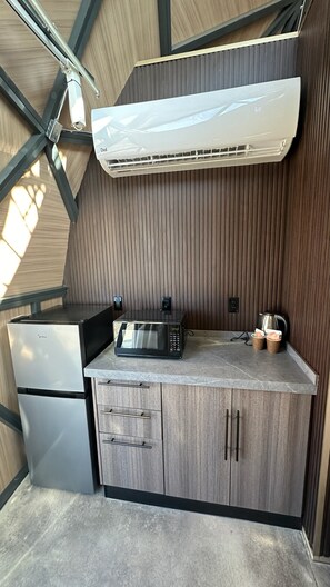 A compact kitchenette with a microwave, a small refrigerator, and a coffee maker on a countertop.