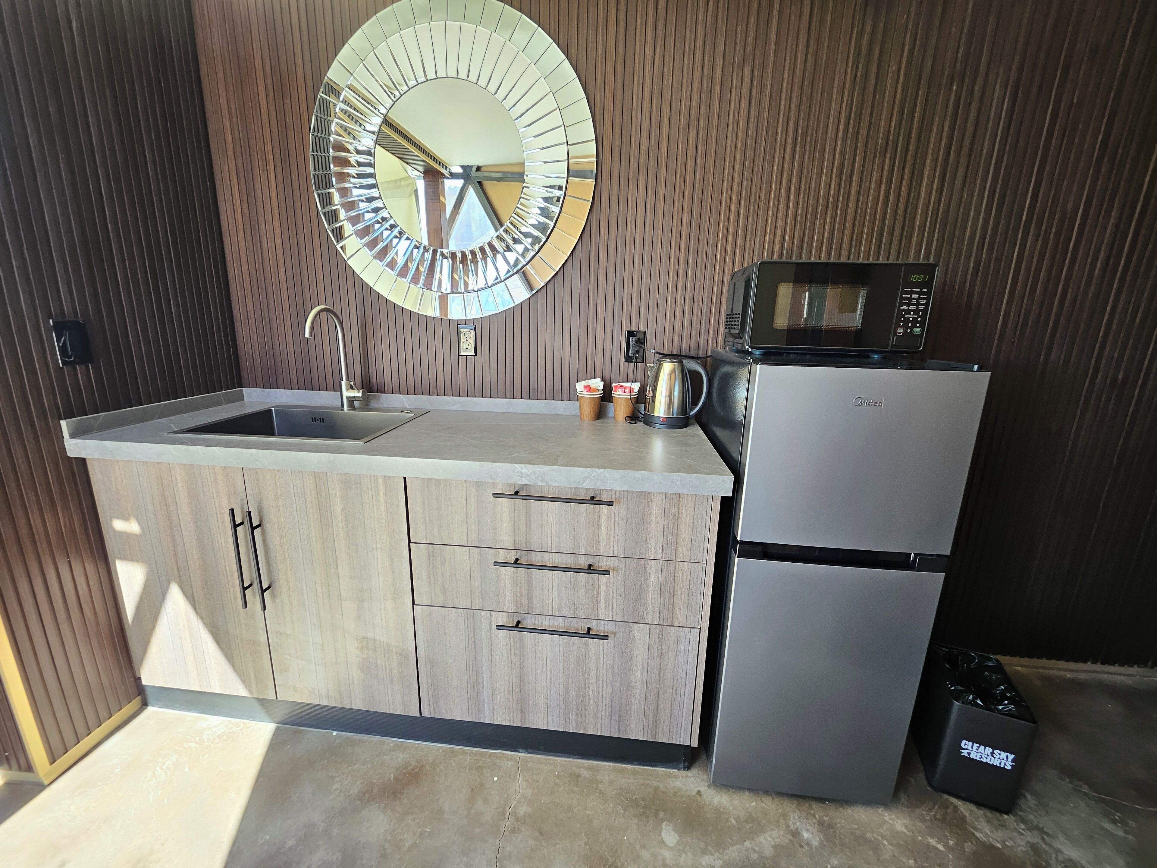 Een moderne keuken met een ingebouwde spoelbak, houten kastjes, een roestvrijstalen koelkast, een magnetron en een koffiezetapparaat.