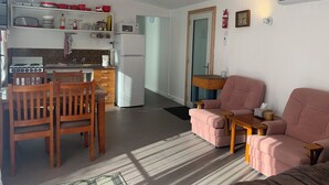 Un espacio habitable compacto con cocina, mesa de comedor y dos sofás.