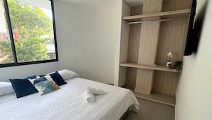 Ein Schlafzimmer mit Bett, Fenster und eingebauten Holzregalen.