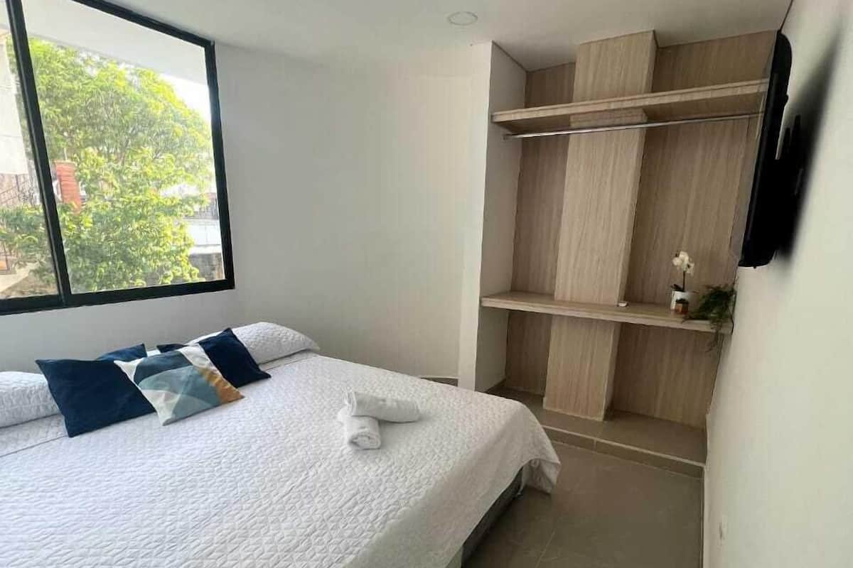Un dormitorio con cama, ventana y estanterías de madera empotradas.