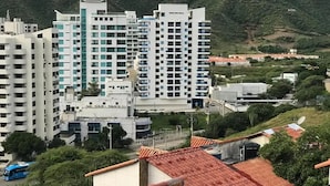 Ein Hochhaus mit mehreren Stockwerken, umgeben von Grünflächen und Hügeln.