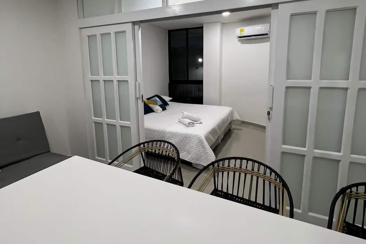Habitación pequeña con cama, escritorio y dos sillas.