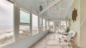 A spacious room with large windows overlooking the beach, white wicker furniture, and a ceiling fan. - Beachfront Alligator Point Retreat: Steps to Sand! (Alligator Point)