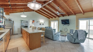 A spacious kitchen with wooden cabinets, a central island, and a dining area with chairs. - Beachfront Alligator Point Retreat: Steps to Sand! (Alligator Point)