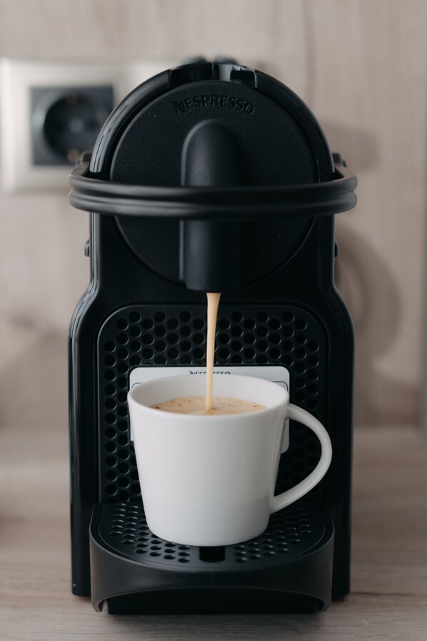 Una cafetera Nespresso sirviendo café en una taza blanca.