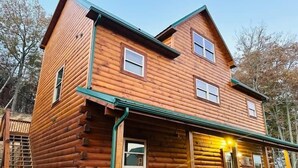 Eine zweistöckige Blockhütte mit überdachter Veranda und einer kleinen angebauten Garage.