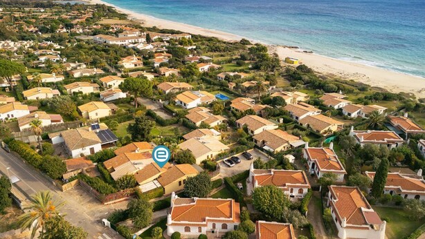 Luchtbeeld van een kustgebied met woonhuizen, een strand en een heldere lucht.