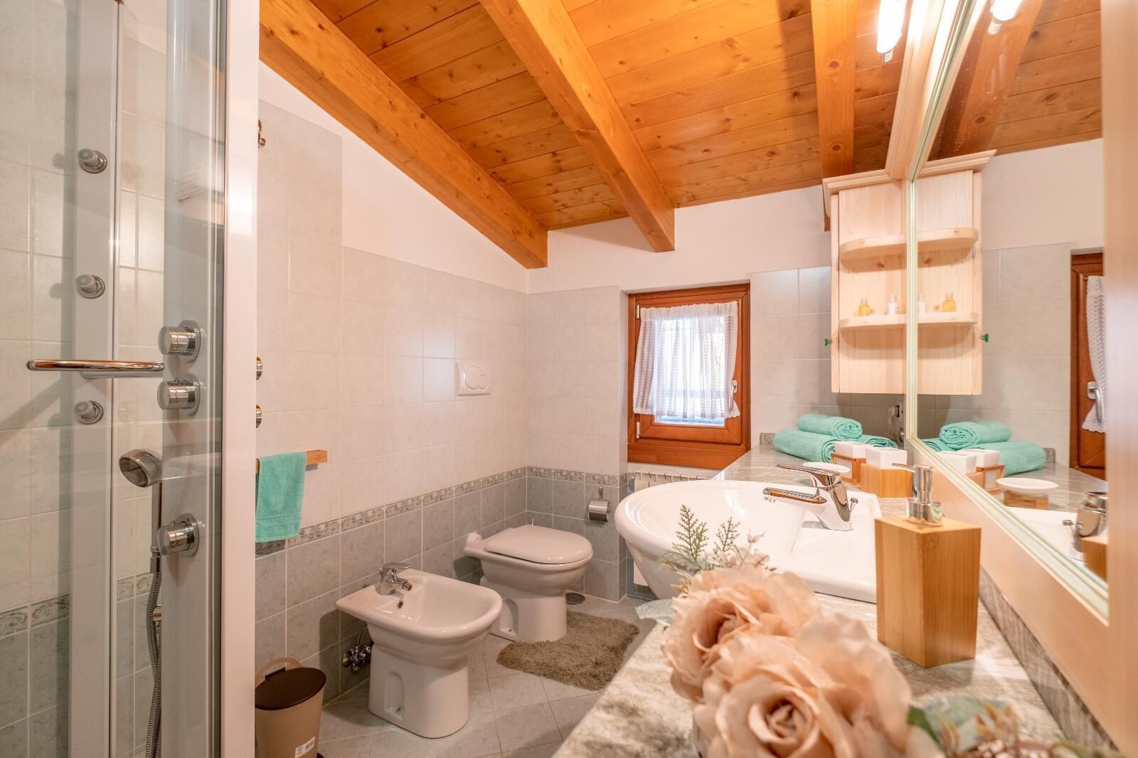 A bathroom with a shower, bidet, toilet, and a large mirror.