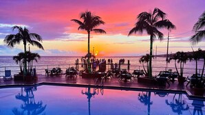 An infinity pool with palm trees and chairs, reflecting the sunset over the ocean. - Luxury Boating Paradise+Pool+Sailing Kayaks (Marathon)