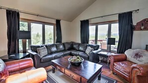Ein geräumiges Wohnzimmer mit einer großen, L-förmigen schwarzen Ledersofa, einem Holztisch und einem braunen Ledersessel.