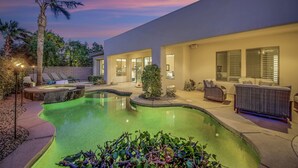 A modern house with a swimming pool, outdoor seating, and a well-lit patio area. - Serenity: Pool,Spa, Gated Community and Fun! (La Quinta)