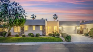 A modern two-story house with a well-maintained lawn, a garage, and a stone facade. - Serenity: Pool,Spa, Gated Community and Fun! (La Quinta)