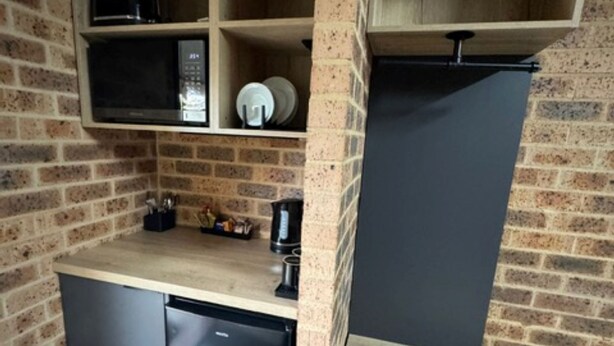 A compact kitchen with a built-in microwave, a coffee maker, and a refrigerator. - Clock Tower Motor Inn (Coonabarabran)