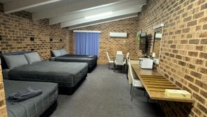 A room with a loft bed, a sofa, a desk, and a chair. - Clock Tower Motor Inn (Coonabarabran)