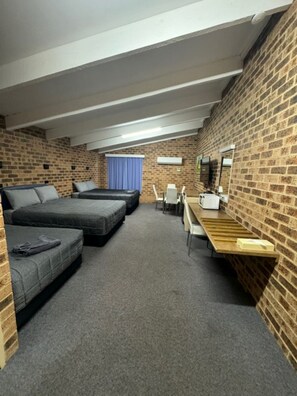 A room with a loft bed, a sofa, a desk, and a chair.