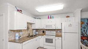 A kitchen with white cabinets, a microwave, an oven, and a refrigerator. - Brower's Plantation Palace

 (Gulf Shores)