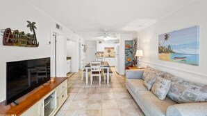 A living room with a flat-screen TV, a sofa, and a dining area with chairs. - Brower's Plantation Palace

 (Gulf Shores)