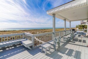 A covered deck with white railings and benches overlooking a beach. - Footprints in the Sand-Oceanfront Home (Navarre)