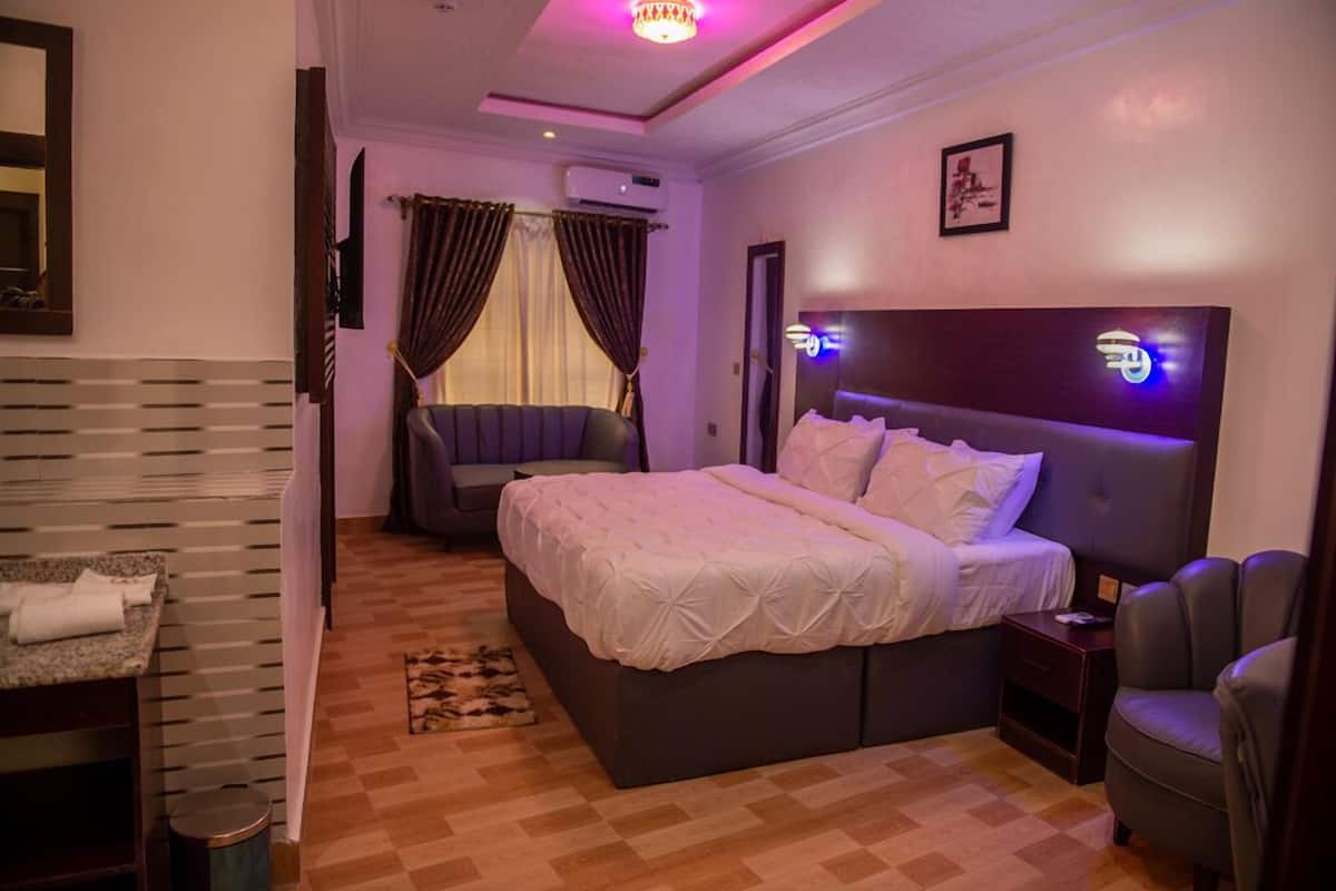 Een hotelkamer met een groot bed, een kleine bank, een bureau en een stoel.