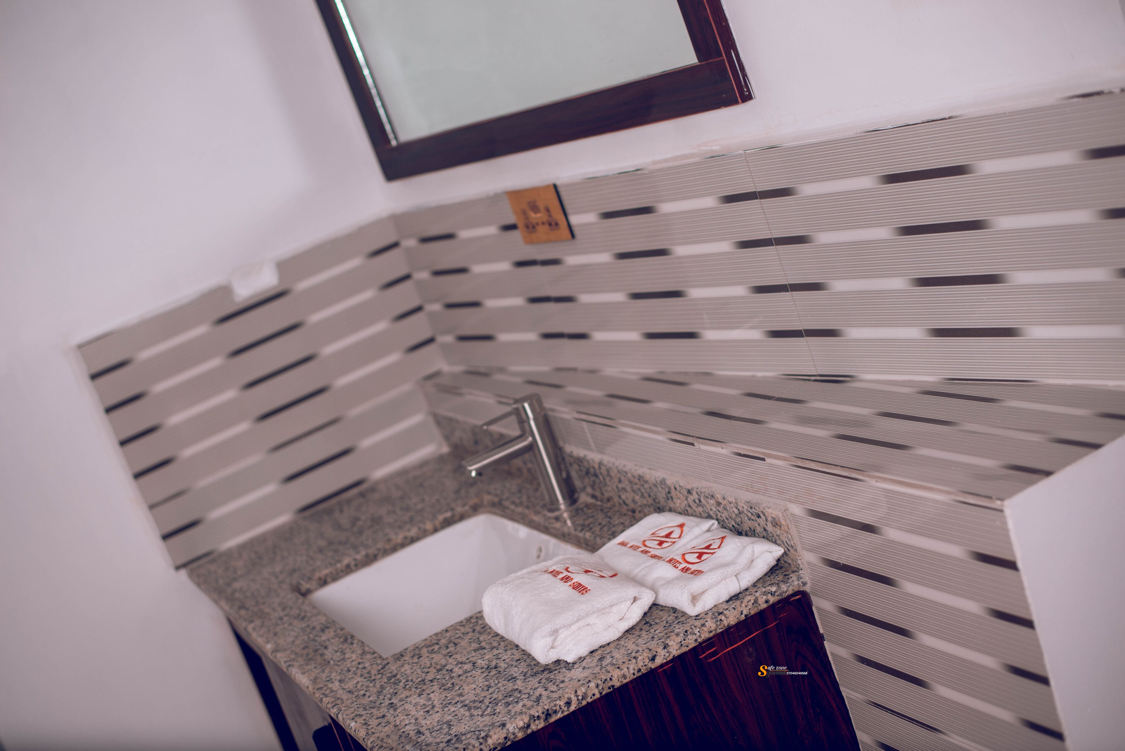 A bathroom with a granite countertop sink, two white towels, and a mirror above the sink.