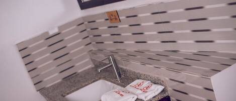 A bathroom with a granite countertop sink, two white towels, and a mirror above the sink.