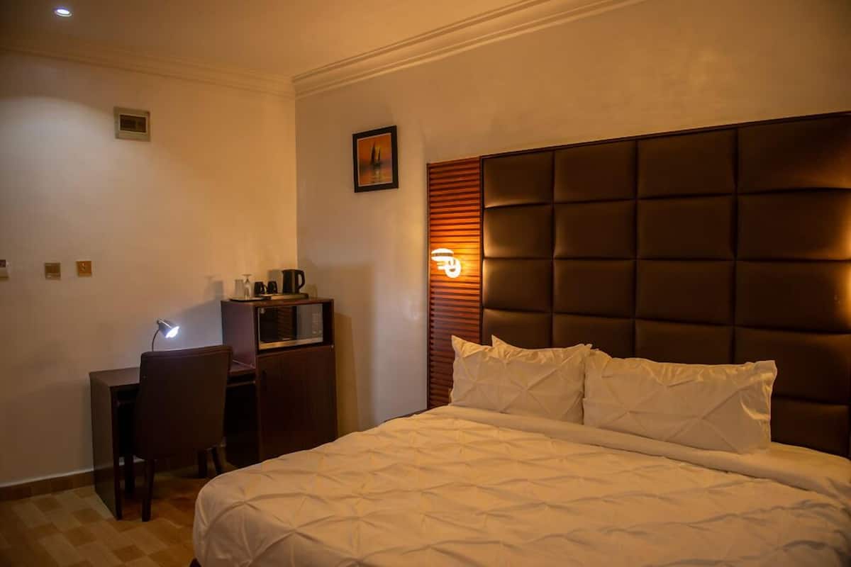 Een hotelkamer met een groot bed, een bureau met stoel en een televisie.