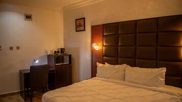 Una habitación de hotel con una cama grande, un escritorio con silla y un televisor.
