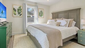 A bedroom with a bed, a nightstand, a dresser, and a window with curtains. - Renovated - Old Village - Close to Beach/Downtown (Mount Pleasant)