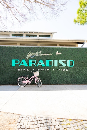 A sign for 'Paradiso' with a bicycle illustration, indicating a focus on dining, swimming, and a vibe.