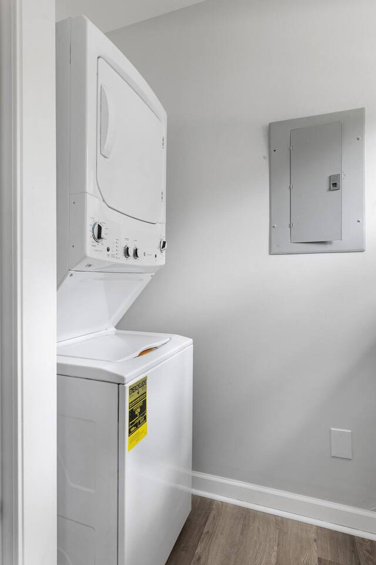 A laundry room with a front-loading washer and dryer, a utility meter, and a wall-mounted electrical panel.