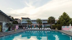 A swimming pool with lounge chairs, a building with a sloped roof, and a sign indicating no swimming. - The Boroughs on Maxwell - 3 Bedroom (North Charleston)