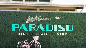 A sign for 'Paradiso' with a bicycle illustration, indicating a focus on dining, swimming, and a vibe. - Stylish 3BR Near Downtown CHS (North Charleston)