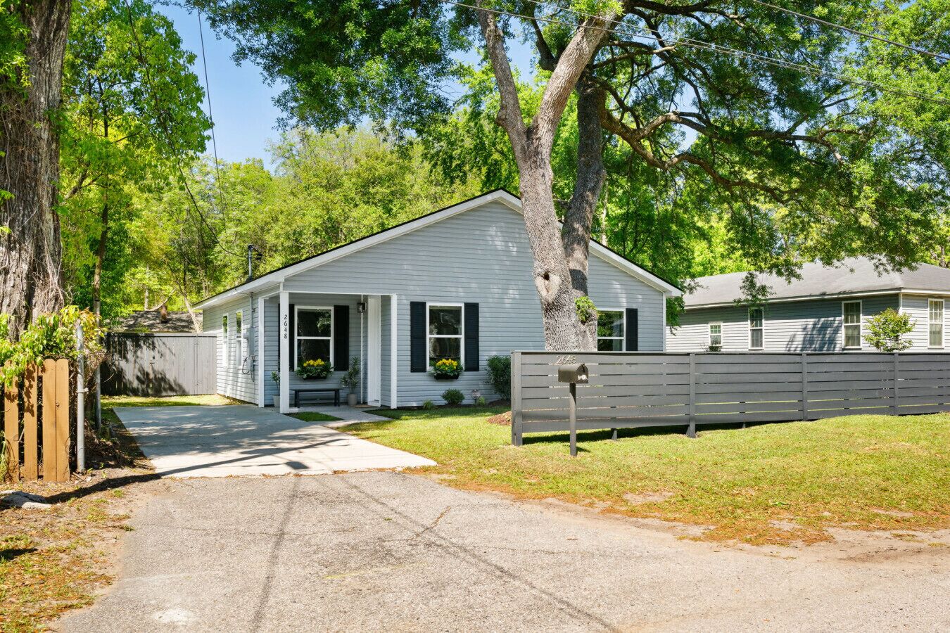 A single-story house with a front porch, a mailbox, and a wooden fence.