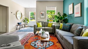 A modern living room with a gray sofa, a coffee table, and a colorful rug. - Stylish 3BR Near Downtown CHS (North Charleston)